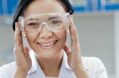 Smiling Asian woman wearing protective eyewear in a healthcare setting