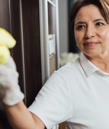 Smiling healthcare worker cleaning window, providing exceptional support services.