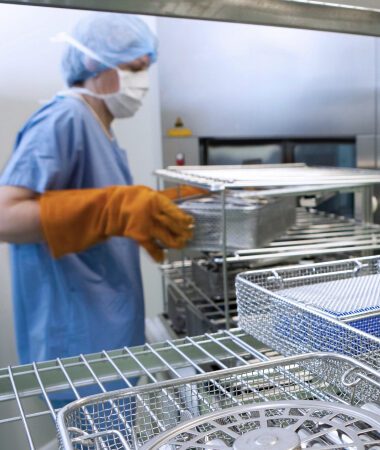 Technician in protective gear disinfecting surgical instruments in sterilization department