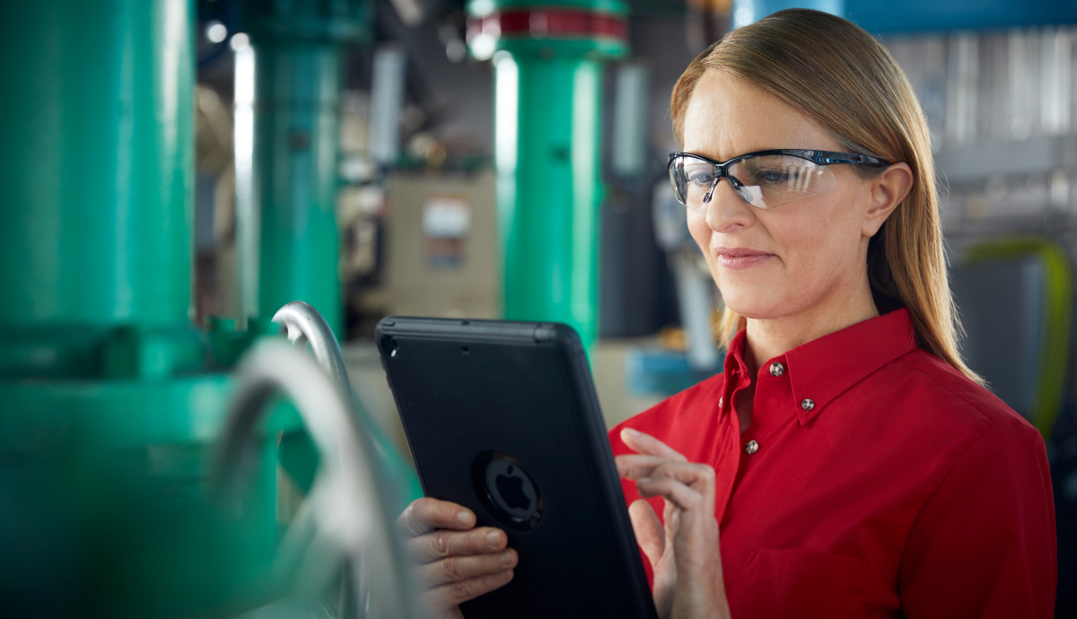Woman in red shirt and glasses using tablet in industrial setting