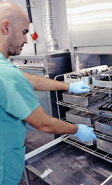 Technician wearing gloves operates sanitizing equipment in industrial kitchen setting