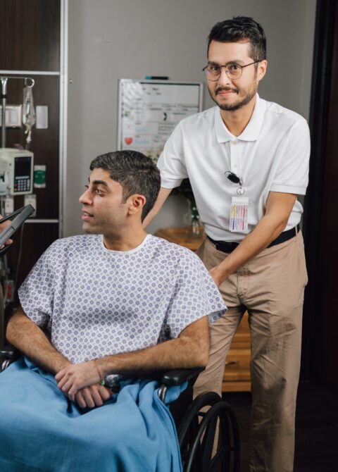 Alt text: Hospital employee helping patient in wheelchair, providing compassionate healthcare support.