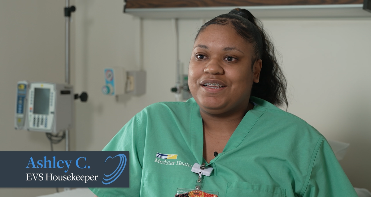Smiling MedStar Health EVS housekeeper in green scrubs at hospital
