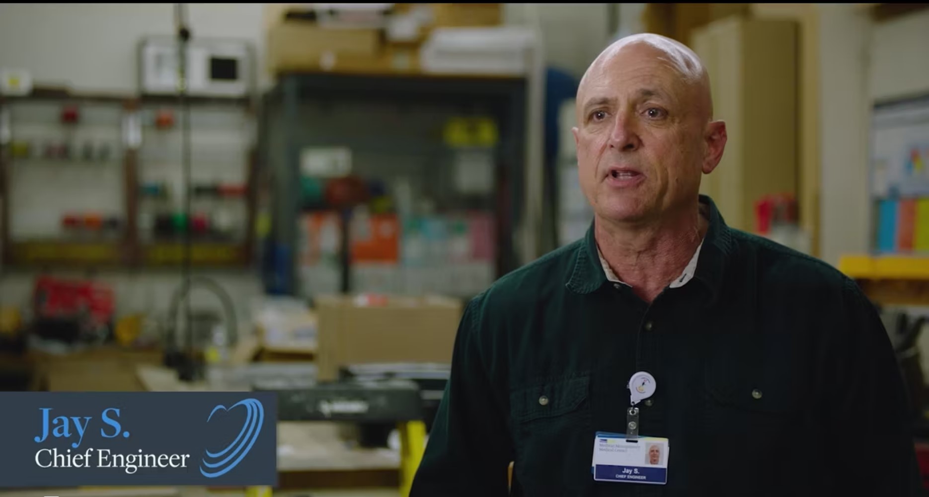Alt text: Chief Engineer Jay S. in a manufacturing facility wearing a black shirt with a name tag